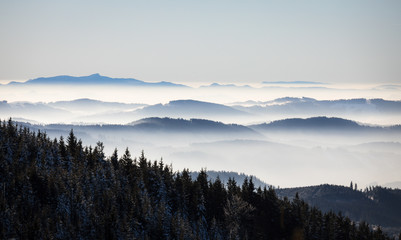 romantic early winter morning in the mountains with foggy valley and distant peaks