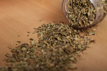 Spice (Oregano) jar lying on wooden table.