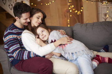 Happy parents with girl relaxing on the sofa