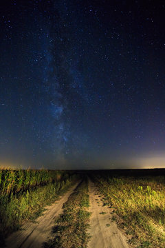Night Starry Sky Above Country Road In Countryside And Green Field