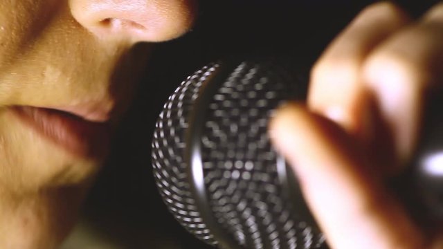 Close up dolly footage of a woman singing to a microphone.