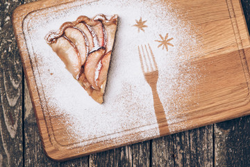 A piece of sliced apple pie with cinnamon on vintage wooden background texture. Top view.