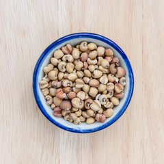Job's tears in bowl on wood floor background.