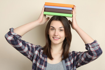 Beautiful girl holding a stack of books on her head.