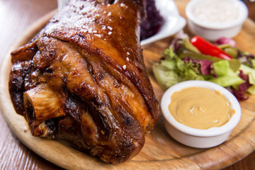 Roasted knuckle of pork with boiled cabbage, horseradish and mustard on wooden background