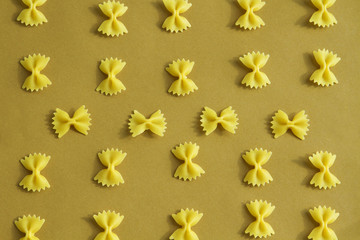 Makaroni or pasta bow shape in row on brown background