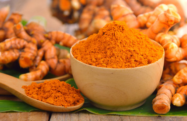 dry turmeric in a wood bowl  with leaf and fresh turmeric on tab
