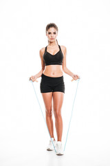 Full length of woman athlete working out with jumping rope