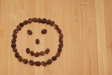 A smile face made from coffee beans on a bamboo background