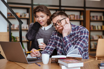 Students sitting at the table with laptop computer in library