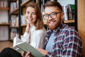 Happy young couple smiling and reading book