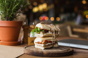 Tasty and appetizing sandwich with arugula and meat on the wooden plate in the restaurant