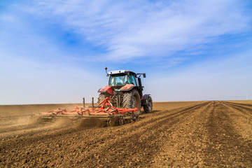 Farmer in tractor preparing land with seedbed cultivator - obrazy, fototapety, plakaty