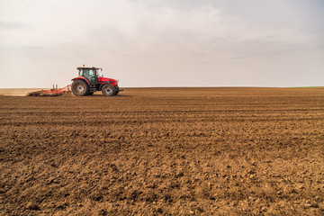 Obraz premium Farmer in tractor preparing land with seedbed cultivator