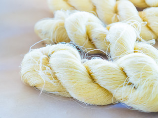 Silk making and production. Closeup of raw golden silk thread on paper.