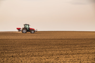 Obraz premium Farmer fertilizing arable land with nitrogen, phosphorus, potassium fertilizer