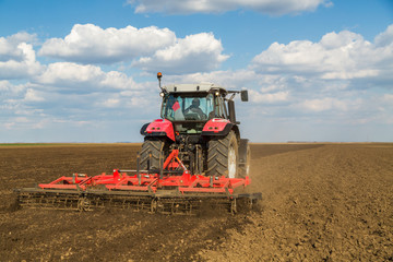 Obraz premium Farmer in tractor preparing land with seedbed cultivator