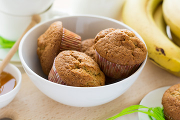Tea time: homemade banana muffins, honey, bananas and tea settings on white wooden table. Selective focus