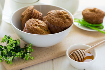 Tea time: homemade banana muffins, honey, bananas and tea settings on white wooden table. Selective focus