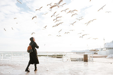 Woman walking on pier and looking at birds in winter