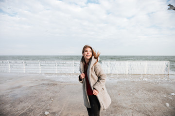 Cheerful woman standing and laughing on pier in winter