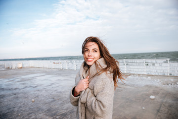 Happy woman standing and smiling on pier in winter