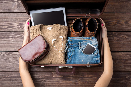 Travel preparations concept with open suitcase and woman's casual clothes