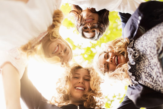 Directly below portrait of happy girls forming huddle at yard