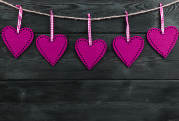 pink hearts on the black rustic wooden background with woodgrain texture