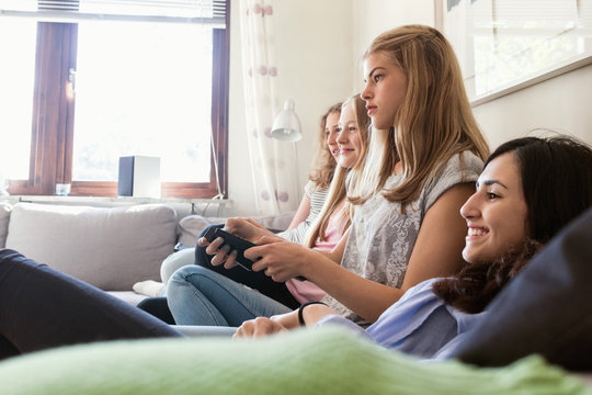 Happy teenage girls watching TV in living room at home