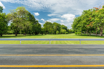Side view of asphalt road with green grass field in park