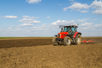Obraz premium Farmer in tractor preparing land with seedbed cultivator as part of pre seeding activities in early spring season of agricultural works at farmlands.