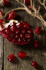 Fresh pomegranate and berries lie on a wooden table.
