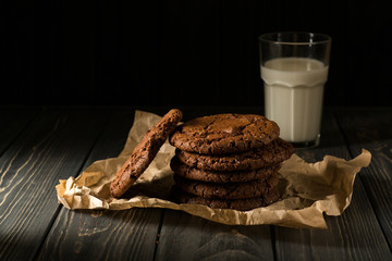 Chocolate cookies on craft paper with glass of milk