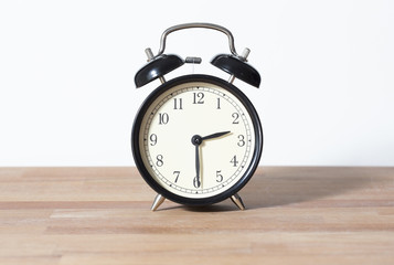 It is half past two o'clock. The time is 2:30. Retro clock isolated on a wooden table. White background.
