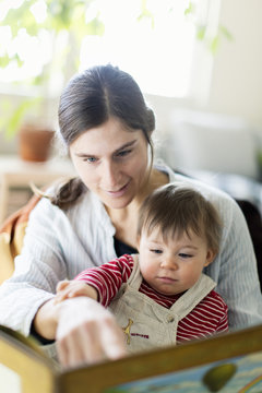 Mother and baby girl reading picture book at home