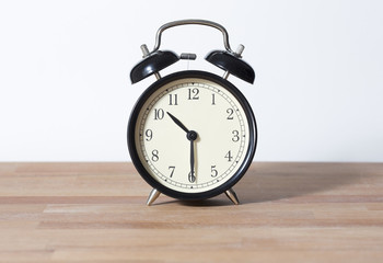 It is half past ten o'clock. The time is 10:30 am or pm. Retro clock isolated on a wooden table. White background.