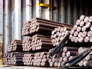 Unstuffing of steel round bar - iron metal rail lines material from container to store in warehouse.