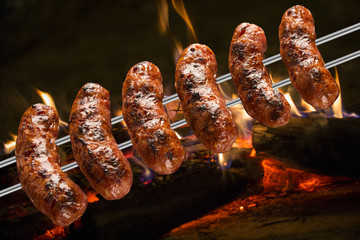 Sausages on the barbecue spit with flames