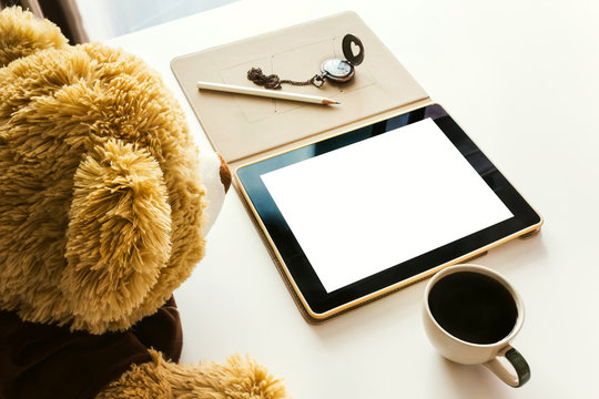 Cute bear doll watching taplet on table