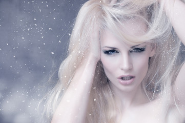 Portrait of a blonde girl with falling snowflakes