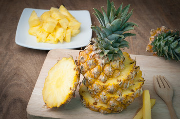 kitchen table with slice fresh pineapple on wooden cutting board