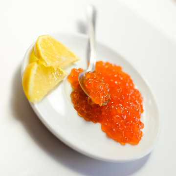 Red caviar with spoon and lemon on white background. Close up image of delicacy food luxury lifestyle