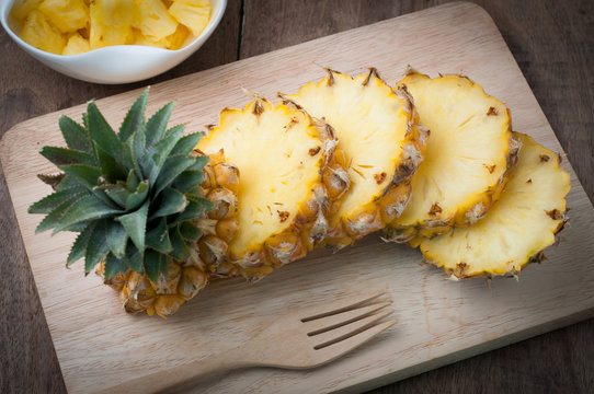 kitchen table with slice fresh pineapple on wooden cutting board.