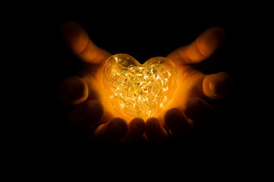 Hands Holding Warm Glowing Orange Heart