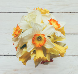 a bouquet of fresh flowers Narcissus on white wooden background, top view