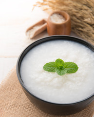 Mush or boiled rice in bowl on wooden table.