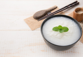 Mush or boiled rice in bowl on wooden table.