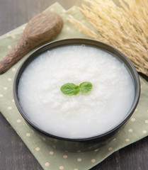 Mush or boiled rice in bowl on wooden table.