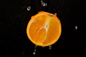 half an orange with drops isolated on a dark background